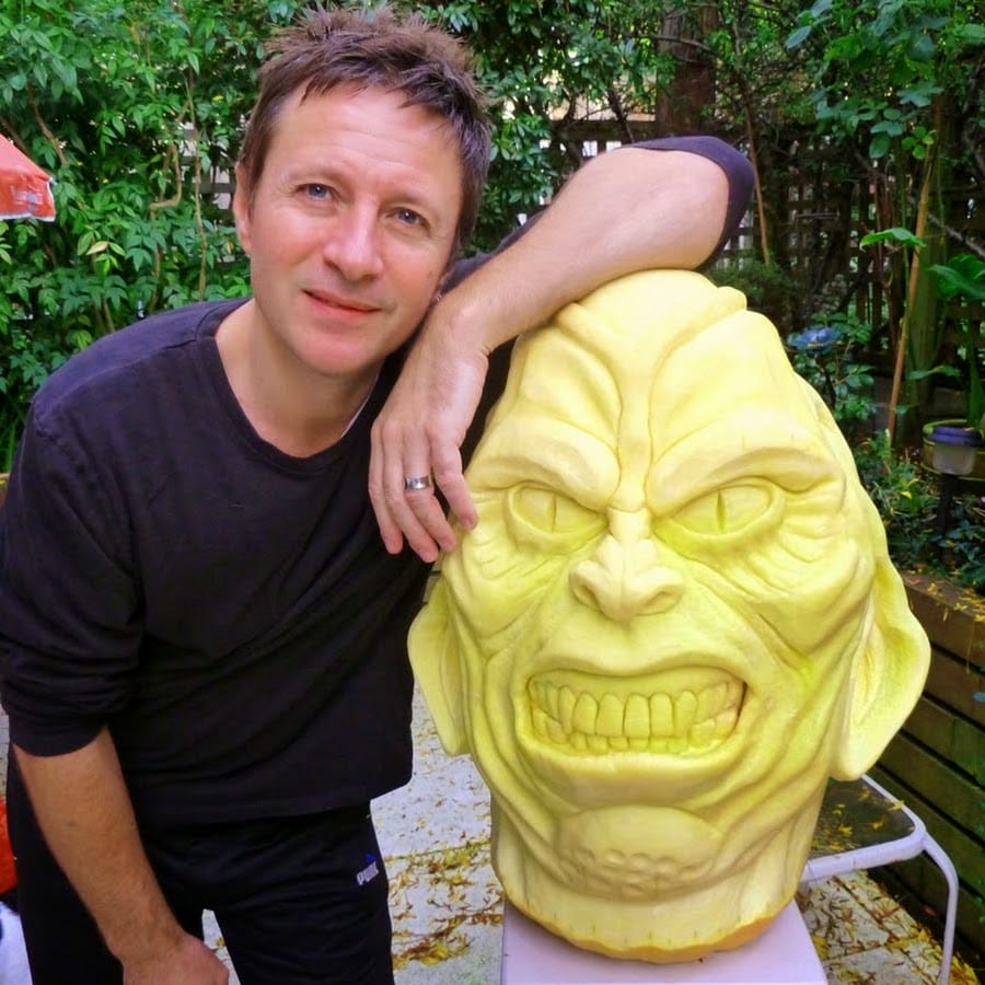 Professional pumpkin carver Clive Cooper standing with one of his carved pupkins