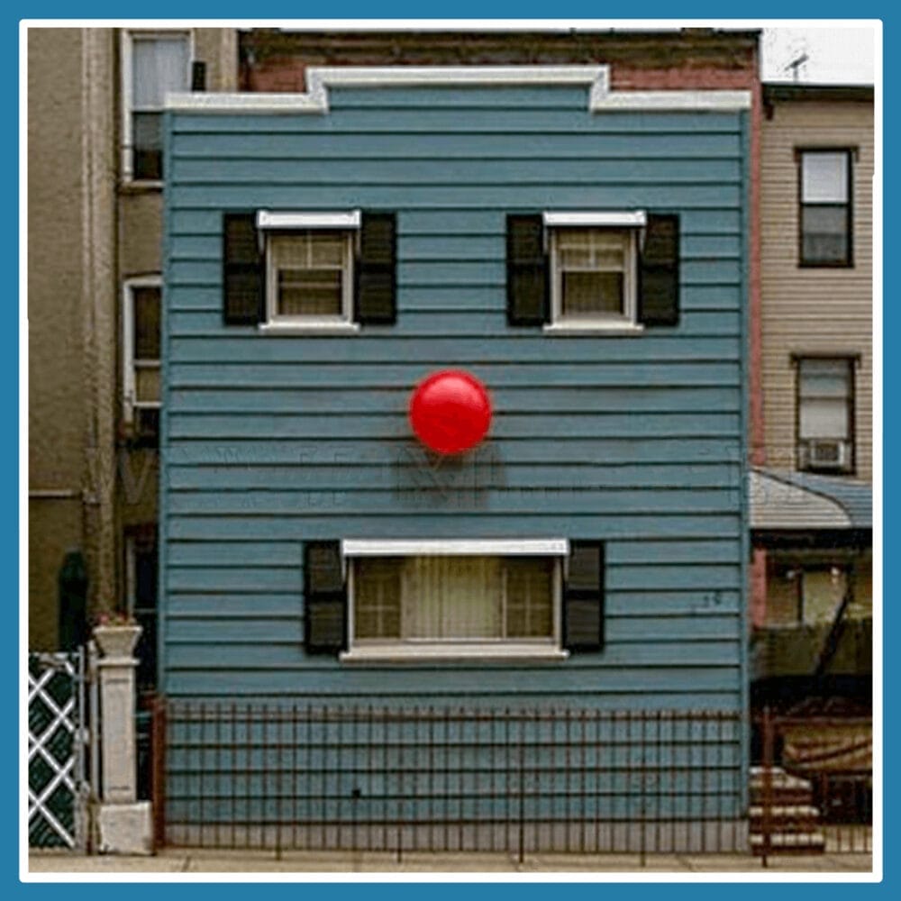 A blue building that looks like a clown as the windows for the mouth and eyes with a red ball in the middle as the nose. 