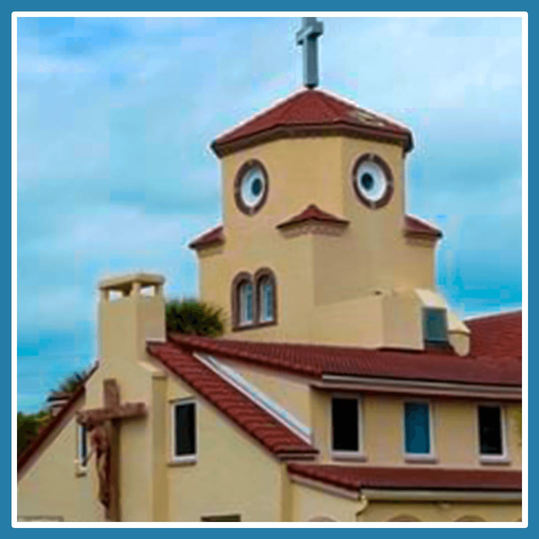 A pale yellow church that looks like it has a duck or face on it's tower roof due to the windows and structure.