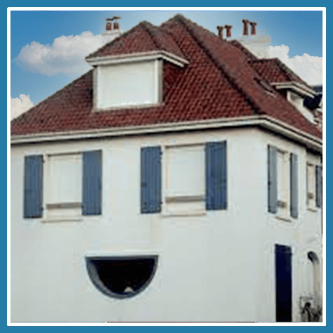 A white house with a red roof that due to the window structure appears smiling.